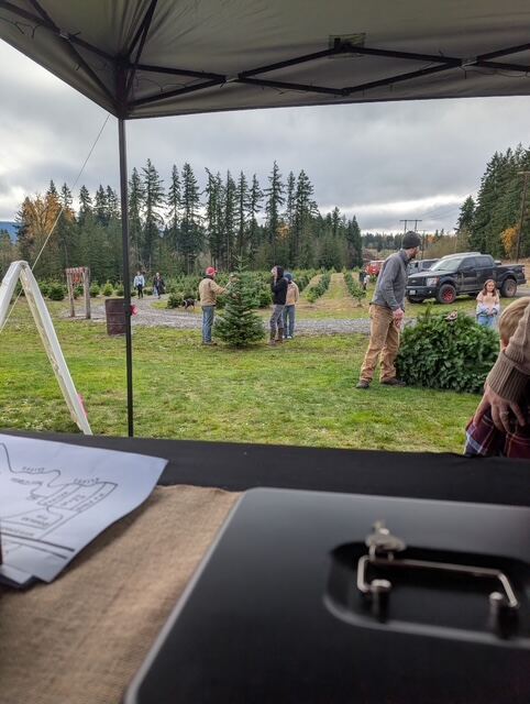 Families at the check-in tent with the tree lot beyond