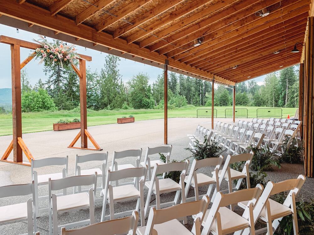 Ceremony set under the covered patio facing a floral arbor and the valley