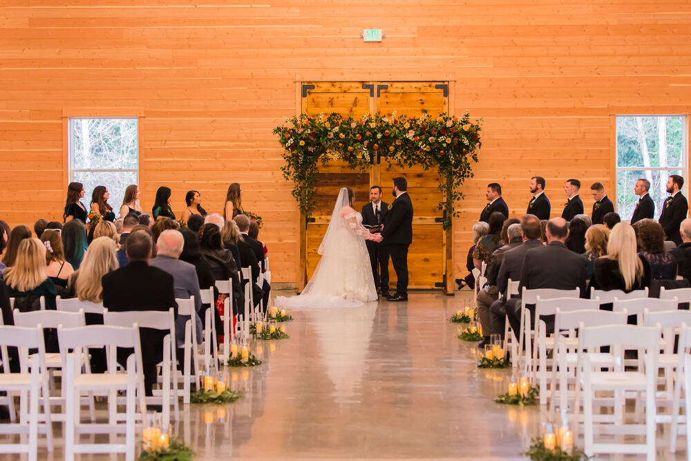 Winter ceremony in the barn with flameless candles lining the aisle
