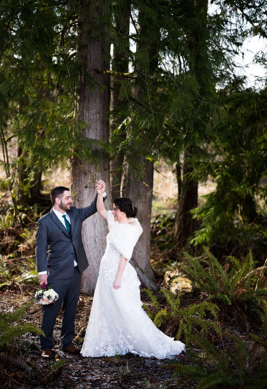 Couple twirling among tall cedars and sword ferns