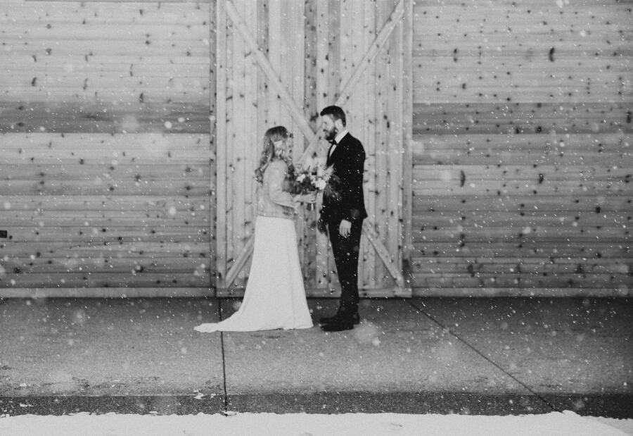 Couple in falling snow at the barn doors, black and white
