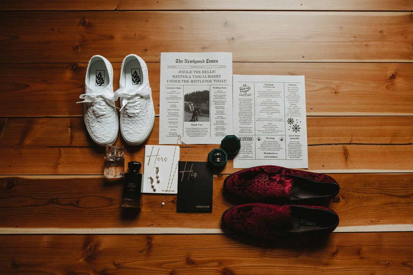 Lace sneakers, velvet loafers, vow books, rings, and a newspaper-style wedding program laid out on a cedar floor