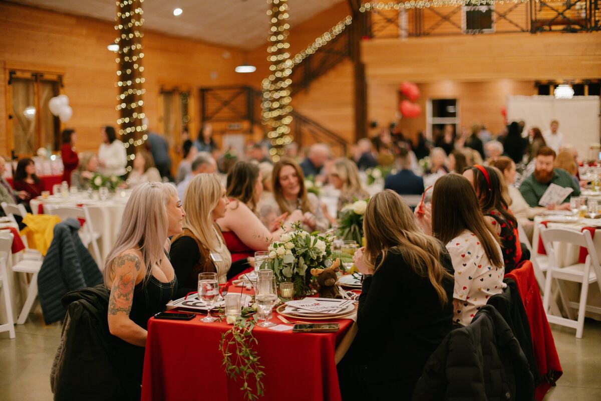 Guests talking at a red-draped table under the string-lit posts