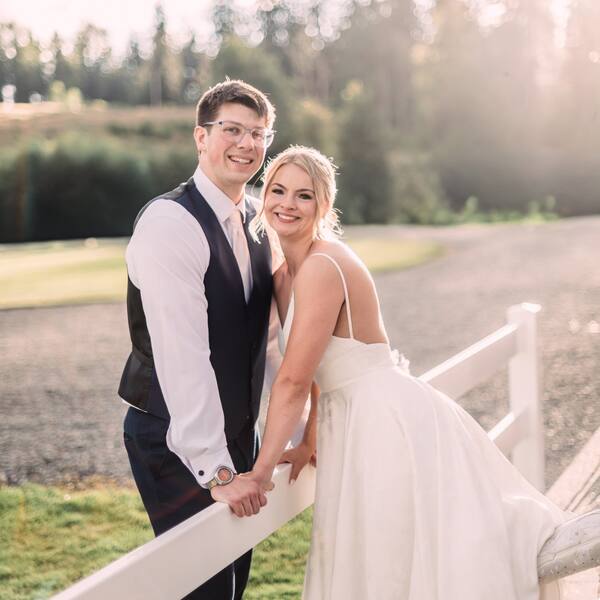 Couple leaning on the white fence by the drive at golden hour
