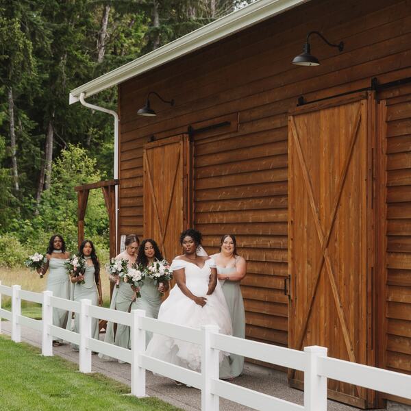 Bride and bridesmaids walking behind the barn