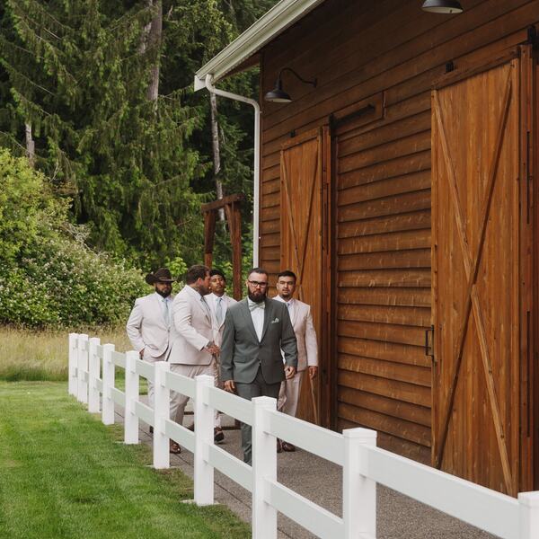 Groom and groomsmen walking behind the barn