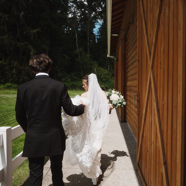 Groom carrying the train along the barn walkway