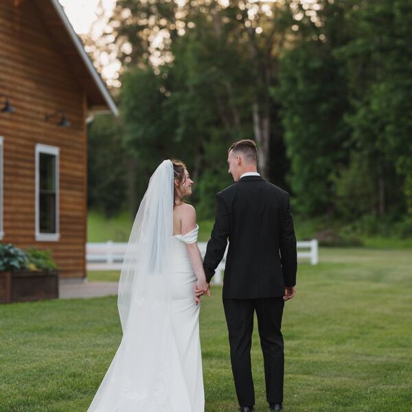 Couple strolling the lawn behind the barn at golden hour