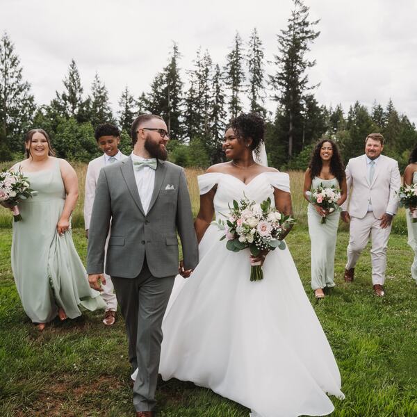 Couple and wedding party walking through the meadow