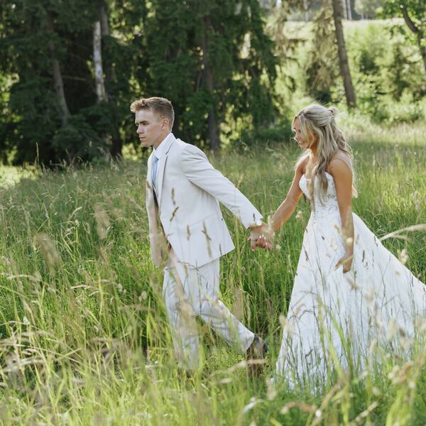 Couple walking hand in hand through tall summer grass