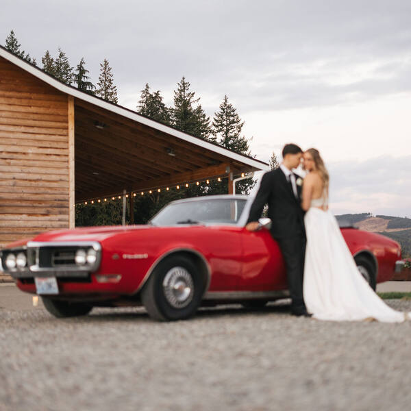 Couple by a vintage red convertible beside the barn