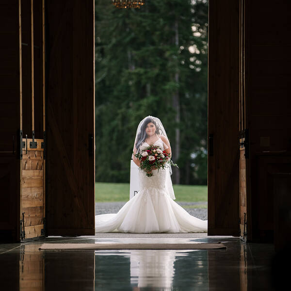 Bride framed in the barn doorway under the chandelier