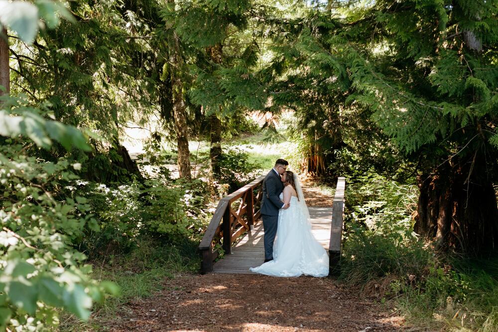 Couple sharing a forehead kiss on the wooden footbridge in the cedar grove