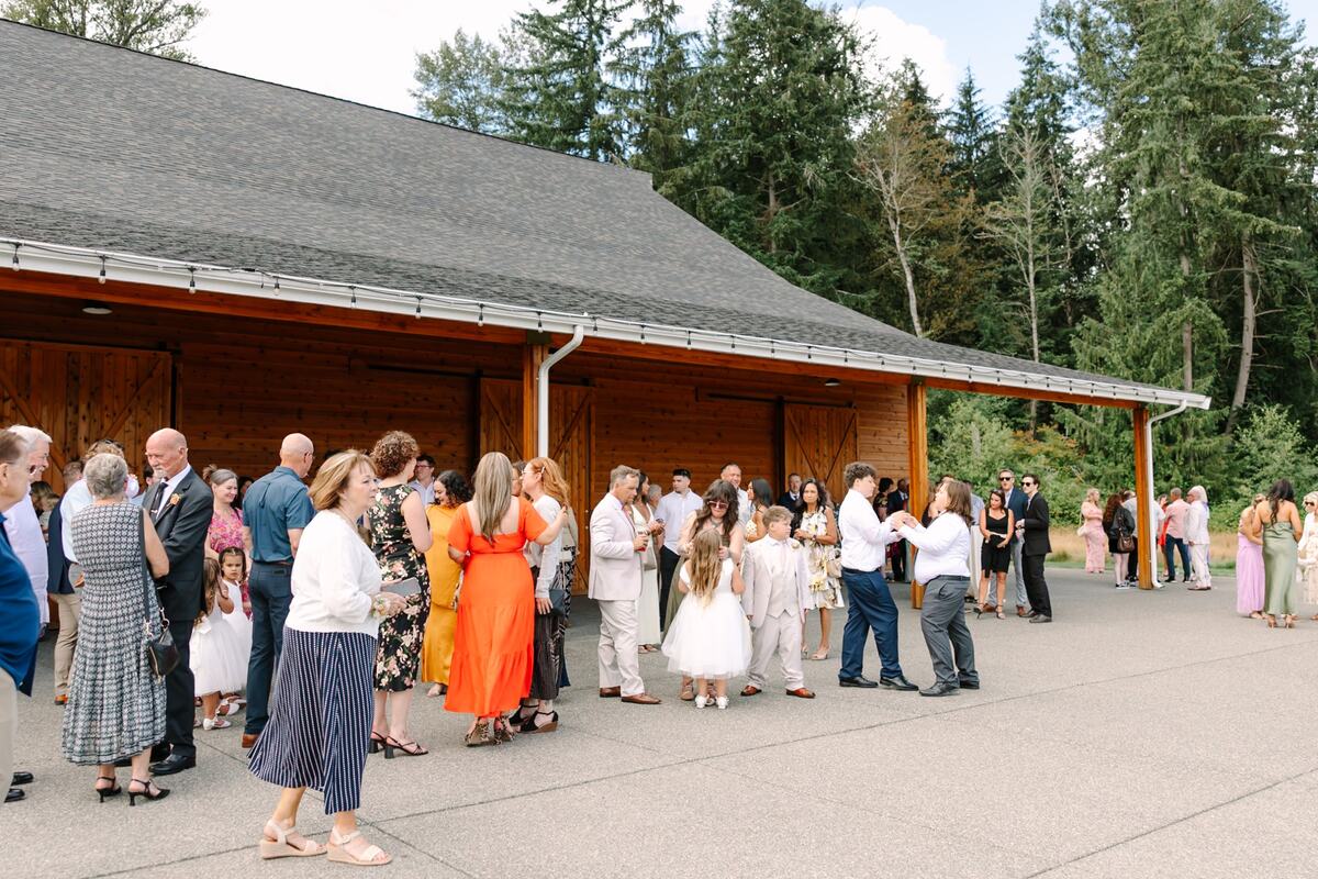 Guests mingling along the barn's covered patio during cocktail hour