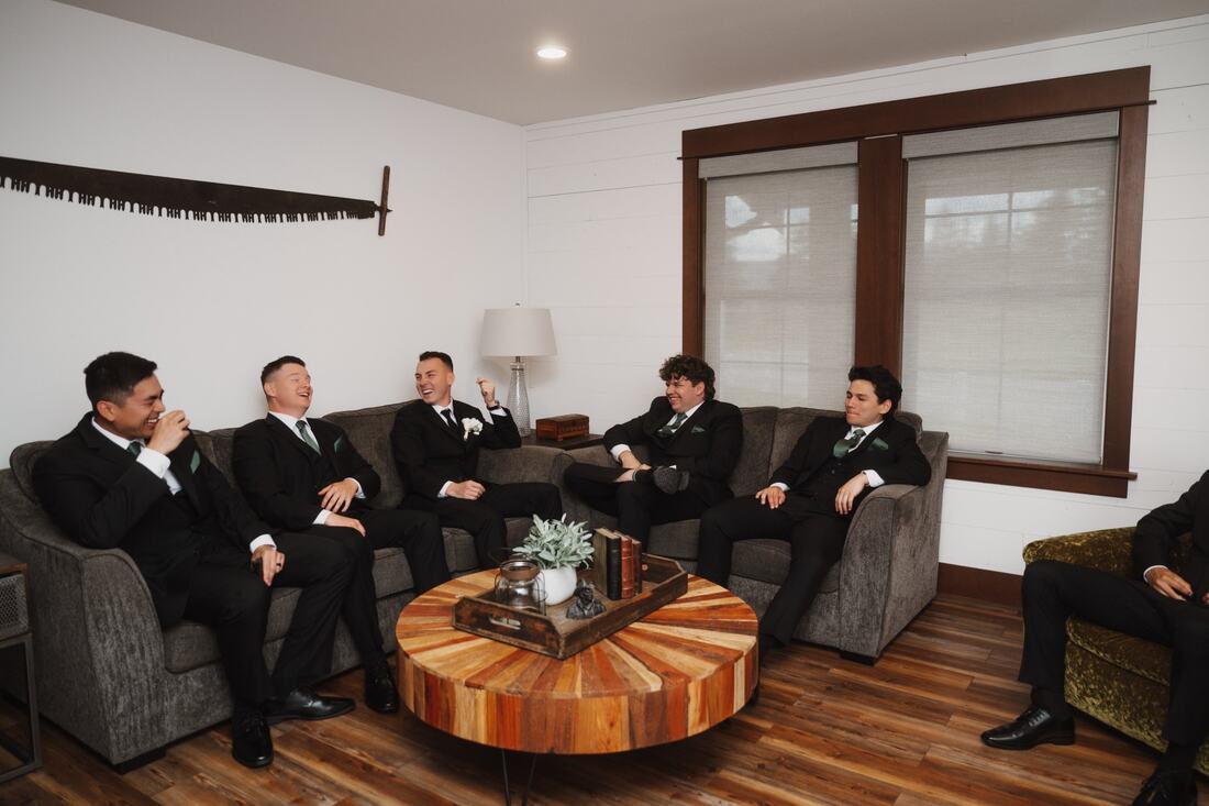 Groomsmen laughing together on the sofas in a getting-ready room