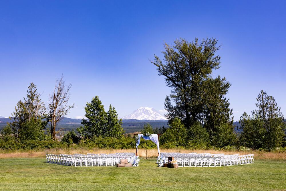 Ceremony chairs set in the meadow facing the arbor and the mountain