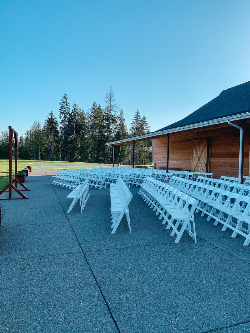 Open Patio set for a ceremony with angled rows of white chairs facing the arbor