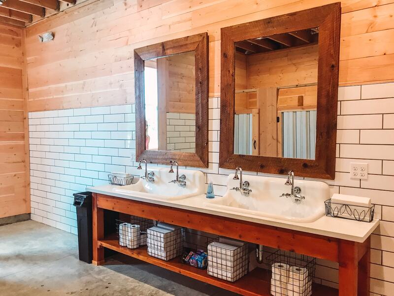 Women's restroom with white farmhouse sinks, subway tile, and cedar-framed mirrors