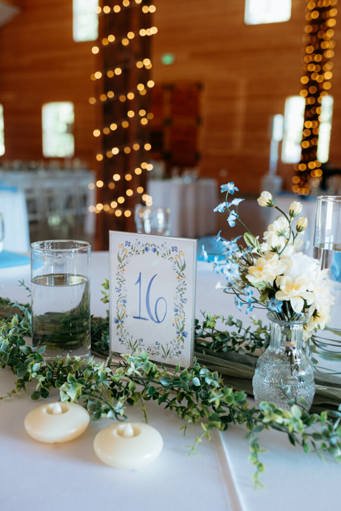 Table number and florals with string-lit posts glowing behind